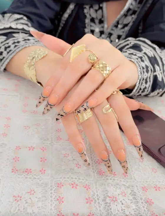 Long stiletto nails with leopard French tips and gold rings